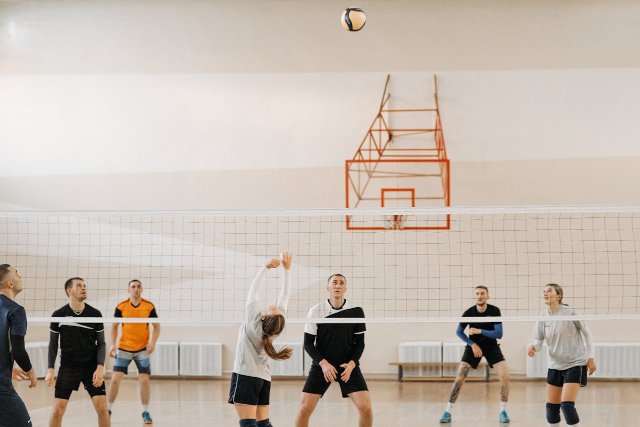 Adults playing an intense indoor volleyball game. Perfect depiction of sportsmanship and teamwork.